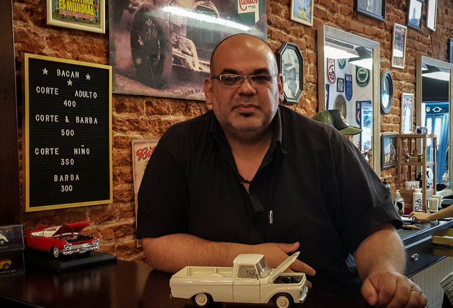 Retrato de Héctor Prahim junto a una camioneta en miniatura